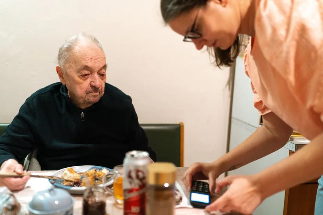 Illustrative stock photo: An older adult receiving assistance at mealtime